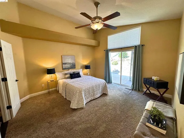 Bedroom featuring access to exterior, carpet flooring, a ceiling fan, and a high textured ceiling