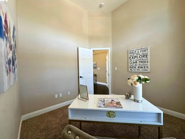 Office space featuring dark colored carpet and a high ceiling