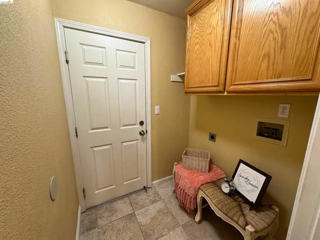 Laundry room with a textured wall, hookup for a washing machine, cabinet space, and hookup for an electric dryer