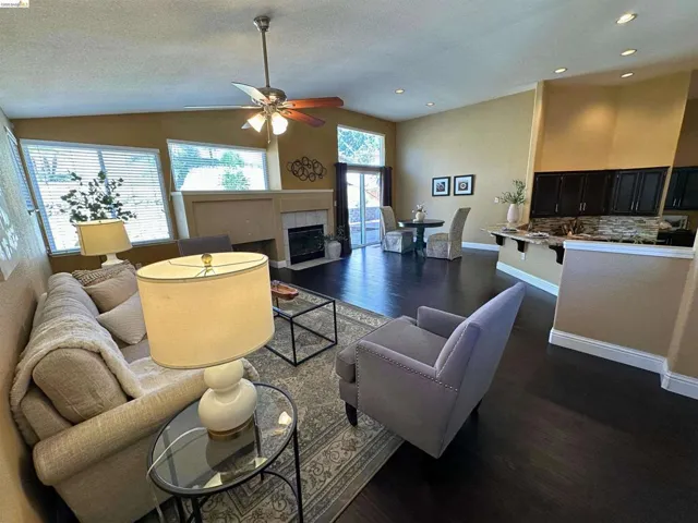 Living room featuring dark wood finished floors, a ceiling fan, a fireplace, and recessed lighting