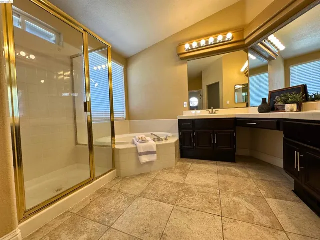 Full bath featuring vanity, a stall shower, a garden tub, and vaulted ceiling