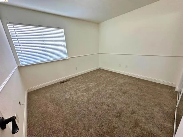 Empty room featuring dark carpet and baseboards