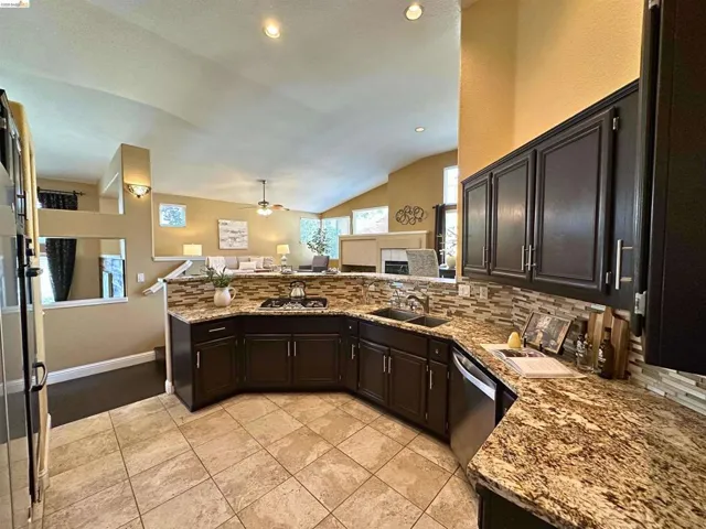 Kitchen with a tiled fireplace, light stone counters, open floor plan, a peninsula, and backsplash