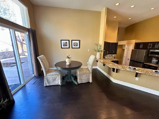 Dining area with dark wood-style floors, a high ceiling, and recessed lighting