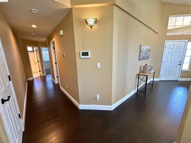 Foyer entrance featuring dark wood-style flooring and a textured wall
