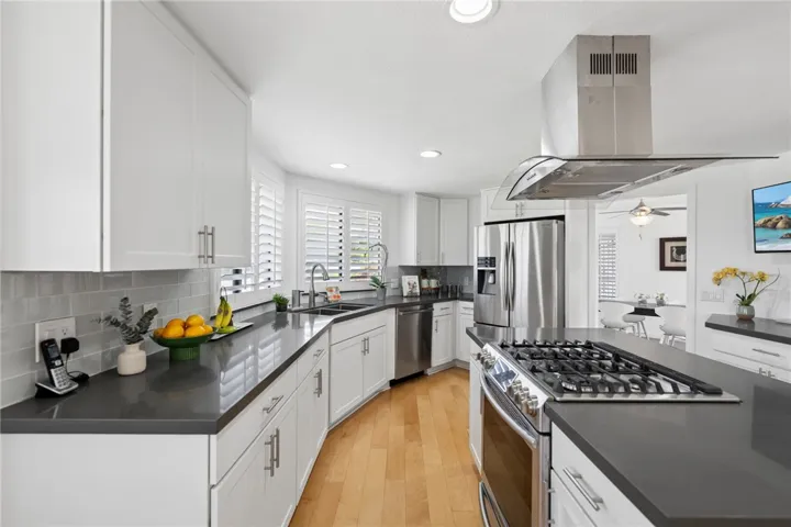 Modern kitchen with stainless steel appliances, substantial cabinetry, and a central island designed for both cooking and gathering. Bright finishes and multiple windows create a fresh, inviting atmosphere.