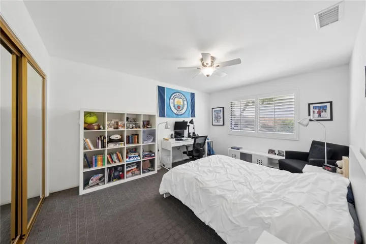Spacious secondary bedroom with plantation shutters, mirrored closet doors, and room for both sleeping and study space. A flexible layout makes it ideal for a guest room, office, or multi-use bedroom.