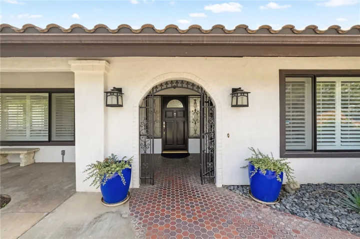 Arched gated entry creates a distinctive arrival, accented by brick-patterned flooring, classic lantern lighting, and decorative planters.