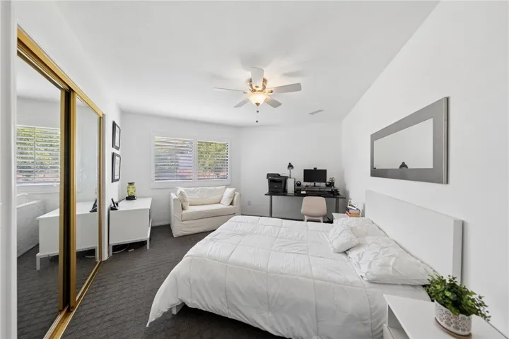 Versatile secondary bedroom with mirrored closet doors, a large window, and space for a desk or guest setup. Ideal for use as a home office, guest room, or flexible bonus space.
