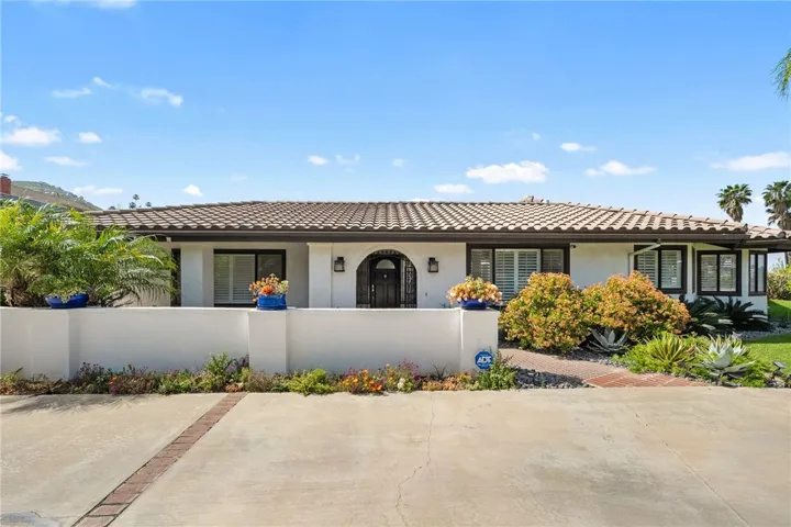 Symmetrical front elevation highlights the home’s broad façade, gated entry, and well-kept landscaping for a polished first impression.