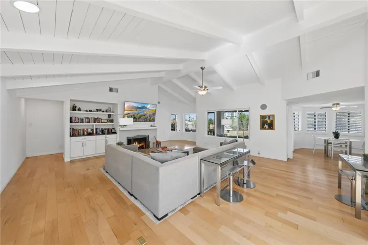 Large great room with soaring beamed ceilings, abundant natural light, and an open connection to the kitchen and dining area. A versatile layout offers plenty of space for gathering and relaxing.