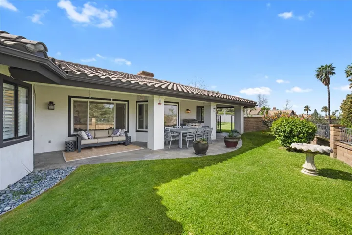 Expansive backyard with a broad lawn, mature palms, and open sightlines creates a peaceful outdoor retreat.