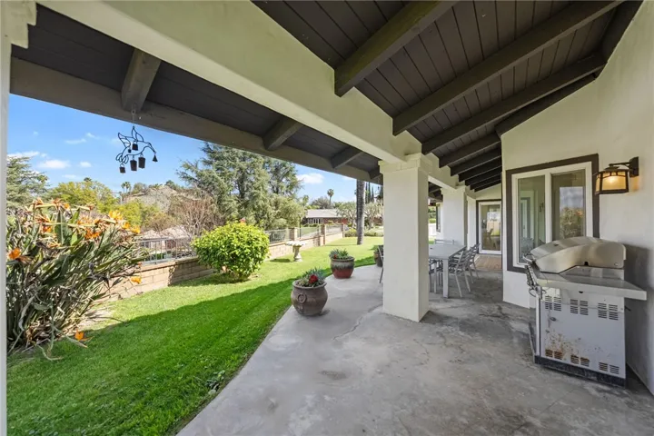 Covered outdoor living area with built-in grill, dining space, and views of the surrounding greenery. Designed for easy outdoor entertaining and everyday enjoyment.