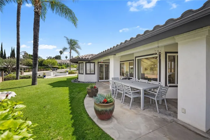 Spacious covered patio opens to a manicured lawn and offers a comfortable setting for outdoor dining and relaxation.