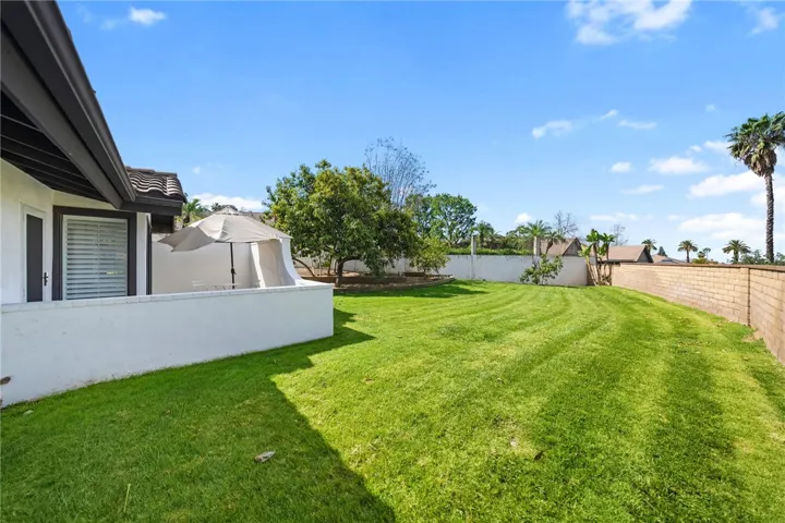 Expansive backyard with a wide stretch of lawn, mature landscaping, and a private patio area tucked just off the home. The generous outdoor space offers plenty of room for play, gardening, or entertaining.