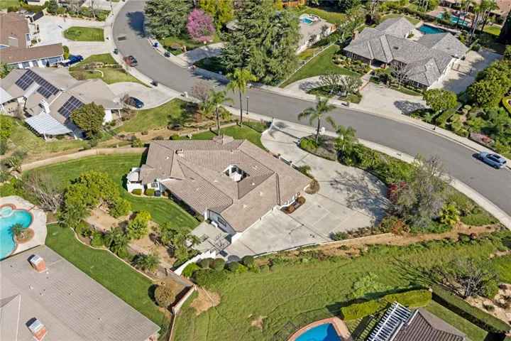 Expansive aerial view showcasing the home’s generous lot, curved driveway, and well-maintained landscaping in an established residential setting.
