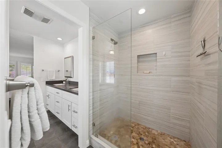 Spacious shower area with frameless glass enclosure and contemporary tilework connects seamlessly to the vanity space. Designed for both style and everyday functionality.