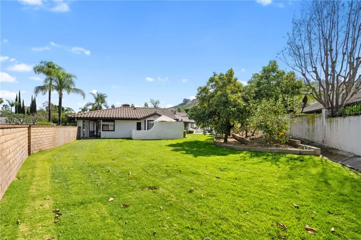 Wide, usable backyard with mature trees, open lawn space, and a private patio area connected to the home. The setting offers a great balance of greenery, privacy, and room to gather.