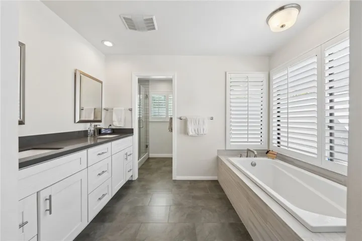 Large primary bath with a double vanity, soaking tub, and separate shower. Bright finishes and a spacious layout create a clean, spa-inspired feel.