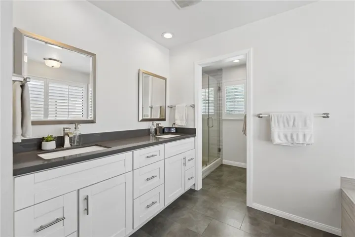 Well-appointed primary bath with dual sinks, ample cabinetry, and direct access to the separate shower area. Crisp white finishes and quartz counters give the space a fresh, updated look.