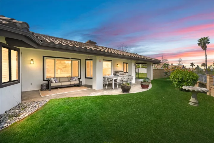 Covered outdoor living and dining areas overlook a lush lawn, creating an easy flow for everyday enjoyment and casual entertaining. Thoughtful landscaping adds color and privacy.