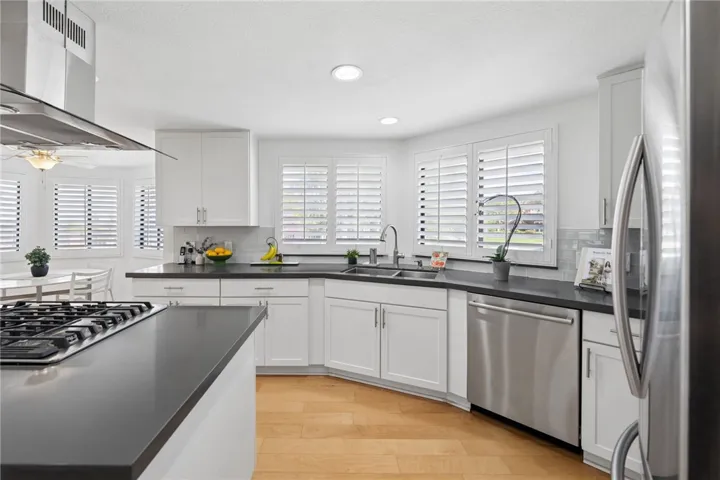 This well-designed kitchen features extensive counter space, a double sink, stainless steel dishwasher, and plantation shutters for a clean, polished look. The layout offers generous prep space and natural light throughout.