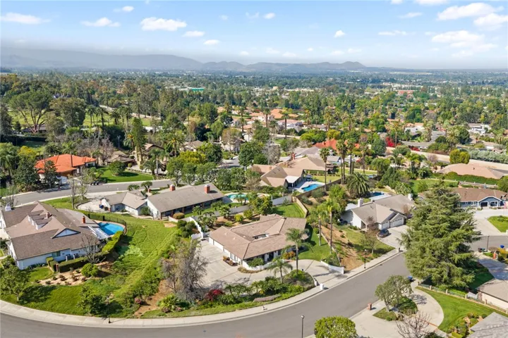 Elevated aerial view highlights the property’s setting within an established neighborhood surrounded by mature trees, rolling hills, and expansive valley views.