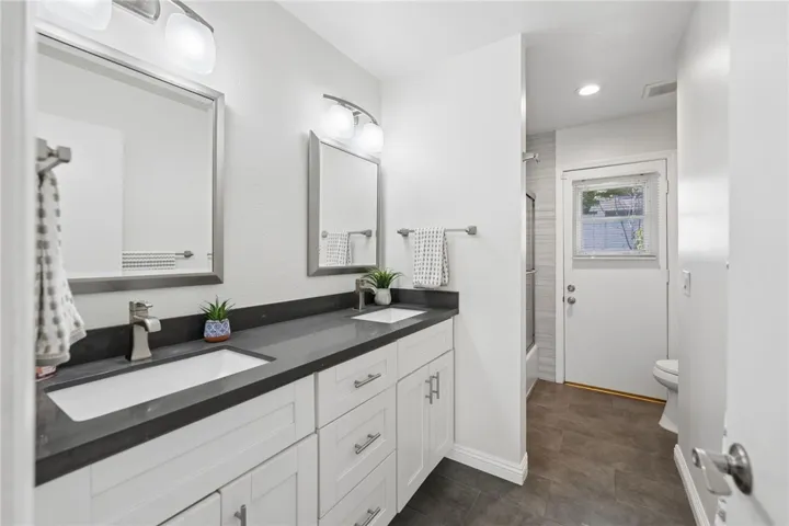 Updated bathroom with a dual-sink vanity, quartz counters, and clean contemporary finishes. The layout offers generous storage and a bright, functional design.