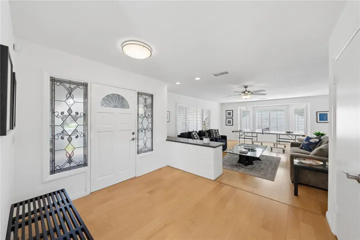 Bright entry foyer opens to the main living area with light wood flooring, crisp finishes, and abundant natural light. The layout offers an open and welcoming first impression.