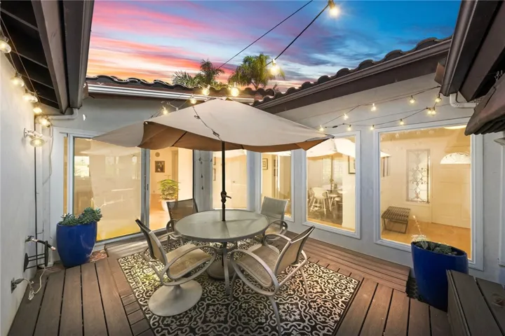 This intimate courtyard-style patio features wood decking, string lighting, and space for outdoor dining. A cozy setting for morning coffee or relaxed evening gatherings.