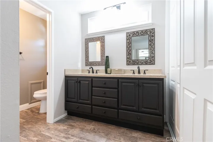 Primary bath has tile floor, dual closets and vanities, and a walk-in shower.