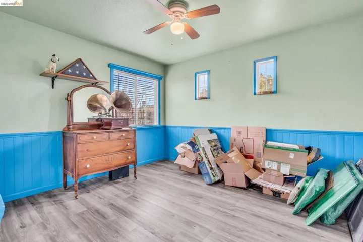 Game room with wainscoting, wood finished floors, wood walls, and a ceiling fan