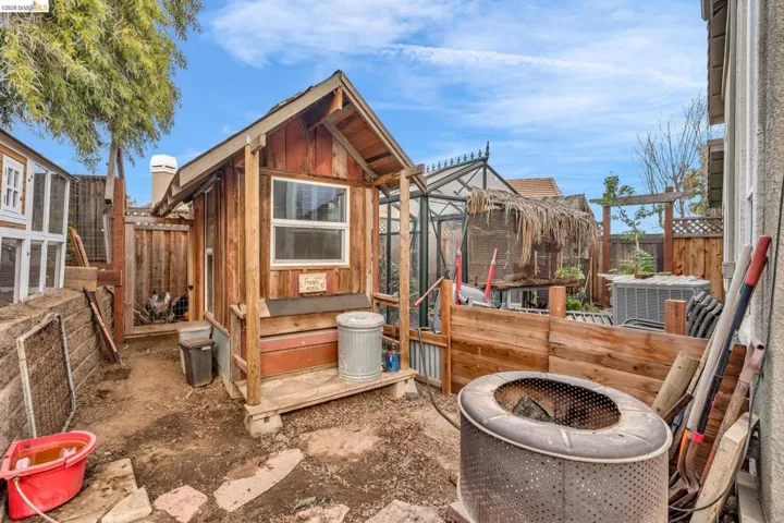 View of chicken coop featuring a fenced backyard and a fire pit