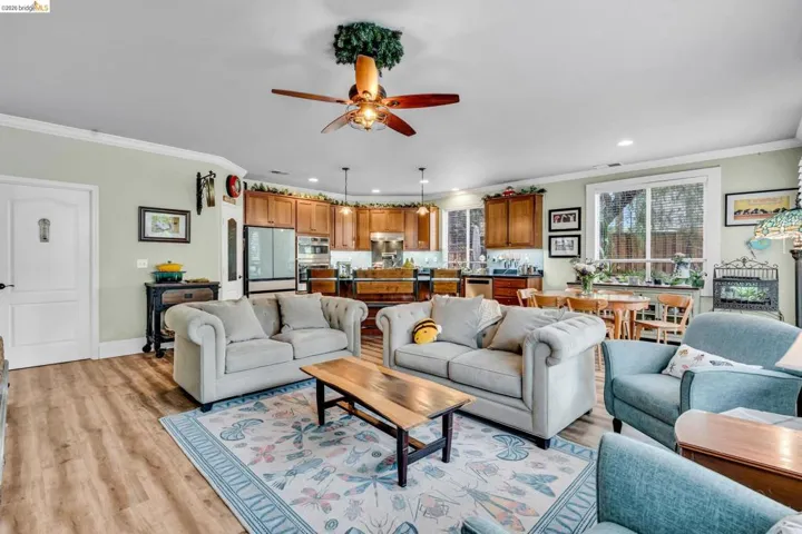 Living room with ceiling fan, crown molding, light wood finished floors, and recessed lighting