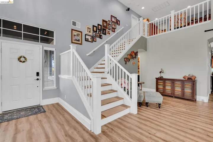 Foyer entrance with a high ceiling, light wood-style floors, and arched walkways