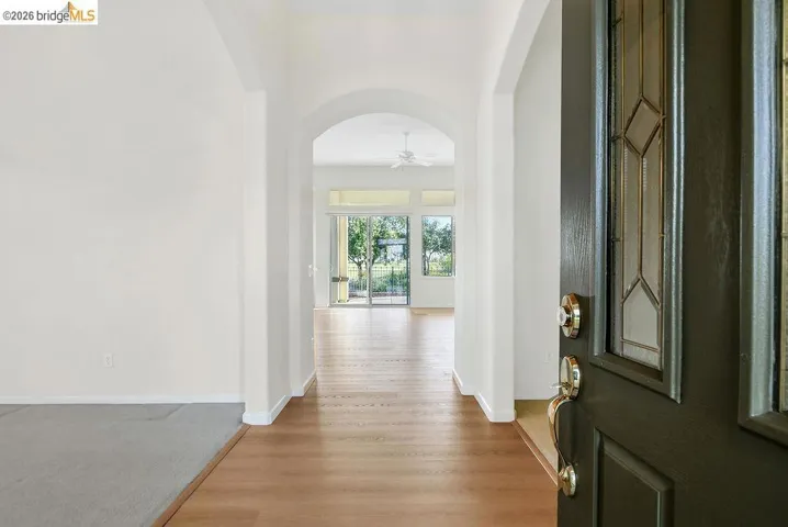 Foyer featuring arched walkways, light wood-style floors, and ceiling fan