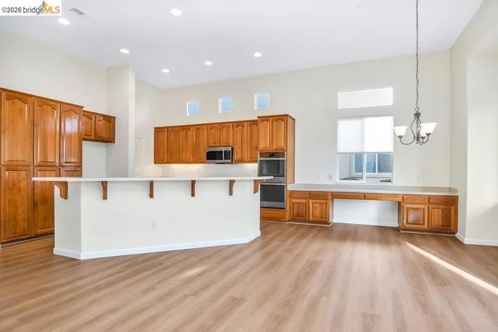 Kitchen with a breakfast bar, wood finish cabinets, a large island, stainless steel appliances, and a high ceiling