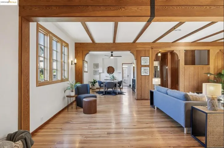 Living area featuring arched walkways, wood walls, beam ceiling, and light wood-type flooring