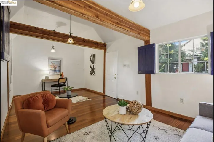 Living area featuring wood finished floors and vaulted ceiling with beams