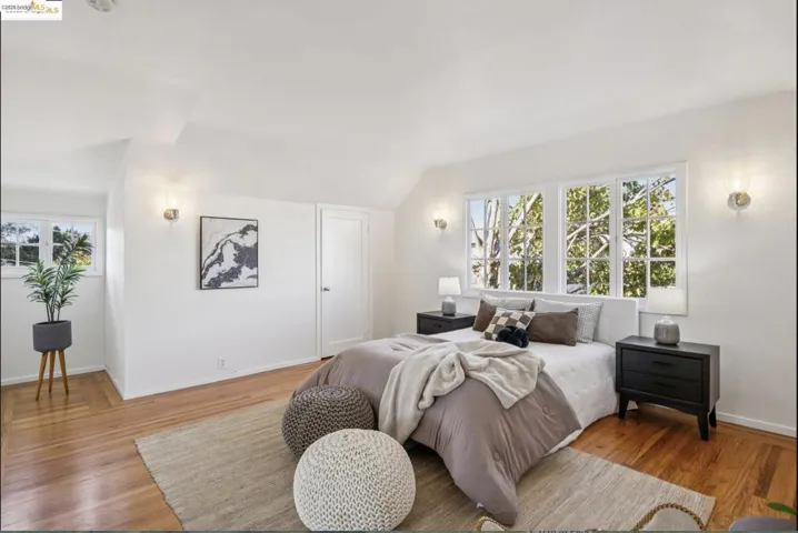 Bedroom with multiple windows, wood finished floors, and lofted ceiling