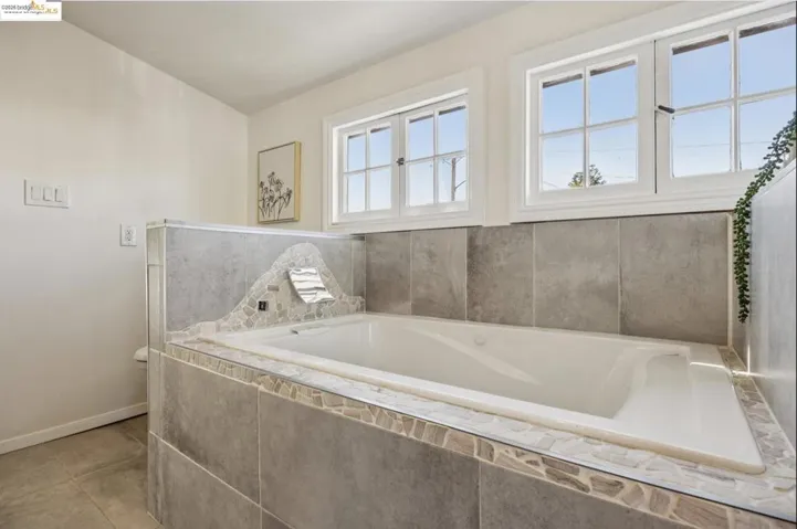 Full bathroom with a garden tub and baseboards