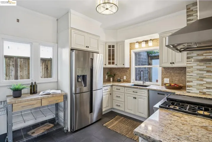 Kitchen with light stone countertops, stainless steel appliances, glass insert cabinets, tasteful backsplash, and ornamental molding