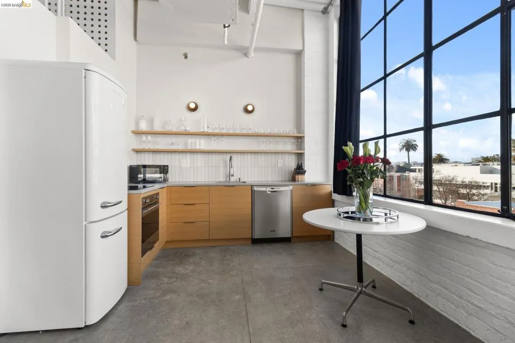 Kitchen with open shelves, stainless steel appliances, concrete floors, light countertops, and modern cabinets