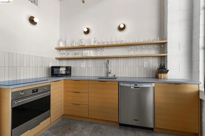 Kitchen featuring open shelves, black appliances, modern cabinets, wood finish cabinets, and dark countertops