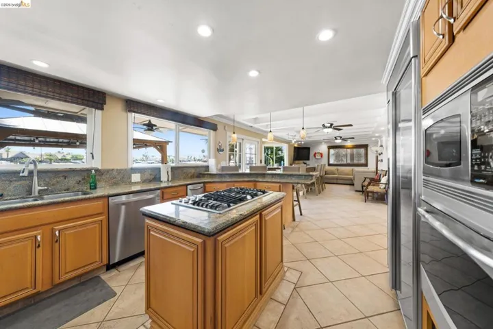 Kitchen featuring recessed lighting, open floor plan, dark stone countertops, light tile patterned floors, and appliances with stainless steel finishes