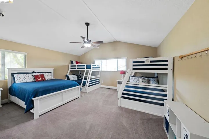 Carpeted bedroom with lofted ceiling and ceiling fan