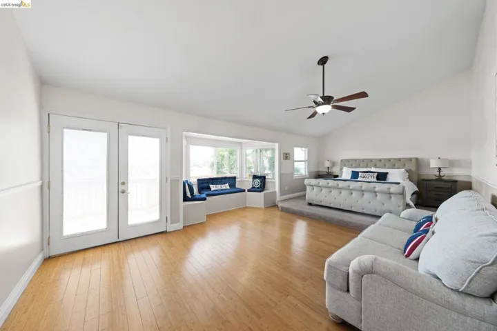 Bedroom featuring lofted ceiling, light wood-style floors, access to outside, a ceiling fan, and french doors