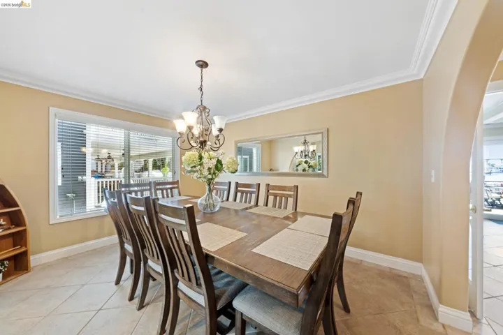 Dining space featuring ornamental molding, light tile patterned floors, arched walkways, and a chandelier