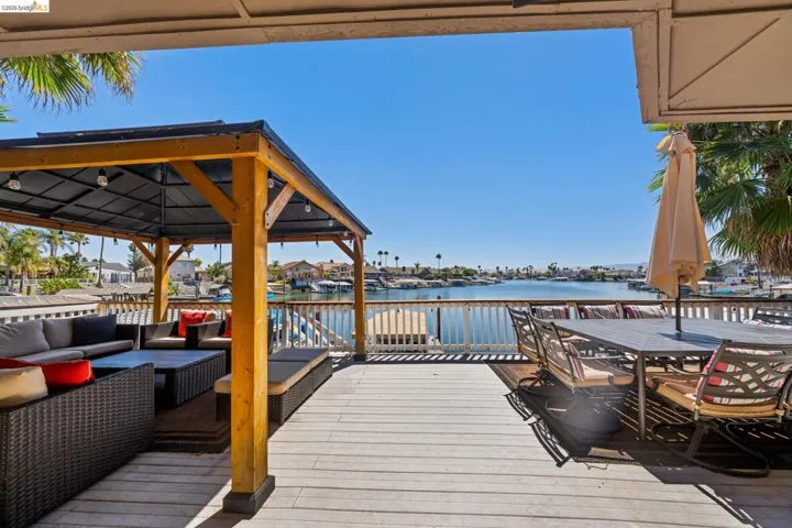 Dock area featuring a deck with water view, outdoor lounge area, a residential view, outdoor dining area, and a gazebo