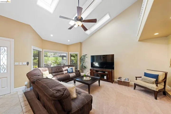 Living area with a ceiling fan, recessed lighting, a skylight, high vaulted ceiling, and light tile patterned floors